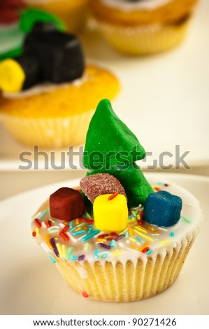 Home-made cupcake with a Christmas Tree decoration.  Out of focus cupcakes in the background
