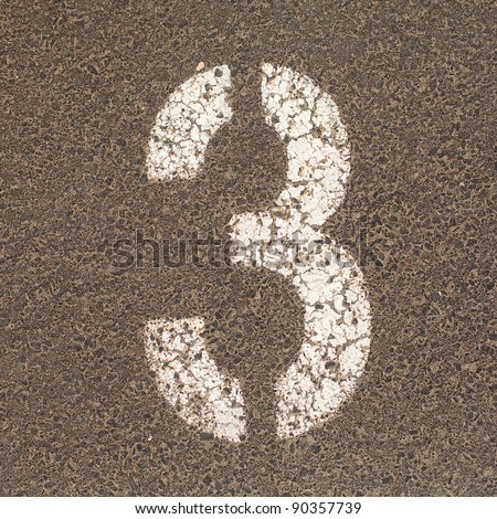 The number Three stencil painted in white on the ground of a  carpark