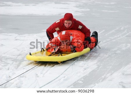 two firemen practicing rescue maneuvers on ice