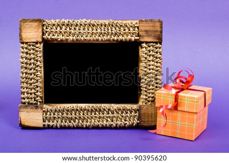 Wooden photo frame and orange gift box with red ribbon on blue background.