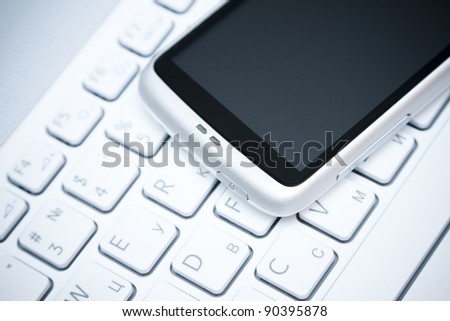 white smart phone on laptop keyboard background