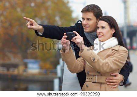 Couple on city trip taking pictures with mobile phone