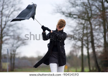 A young woman is fighting against the storm with her umbrella Royalty-Free Stock Photo #90414193