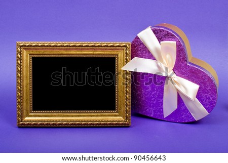 Gold photo frame and heart gift box with ribbon on blue background.