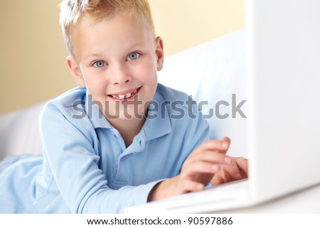 Portrait of cute boy typing and looking at camera