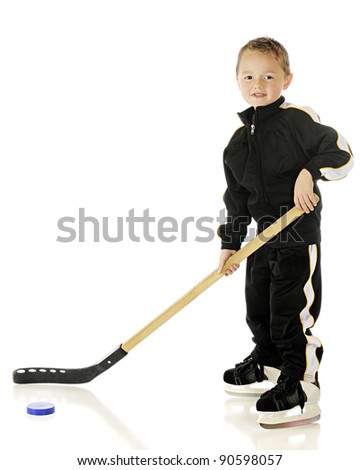 An adorable preschooler ready to play hockey in his skates and uniform.  On a white background.