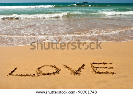 inscription "LOVE" on wet golden beach sand