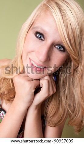 Beautiful young teen blonde poses in the studio in front of a green background.