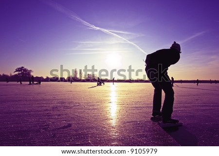 Lonely ice skater at a purple sunset on a lake in the countryside from the Netherlands