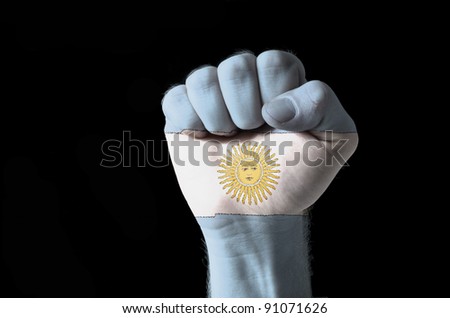 Low key picture of a fist painted in colors of argentina flag