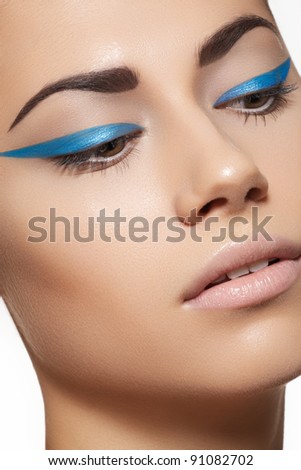 Glamour close-up portrait of beautiful woman model face with winged bright blue eyeliner make-up, clean skin on white background Royalty-Free Stock Photo #91082702