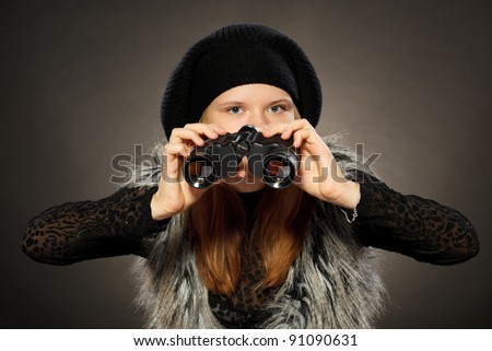 Front view of teenager girl in winter clothing looking through binoculars