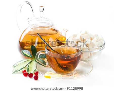 Glass teapot and cup with tea in morning sunlight