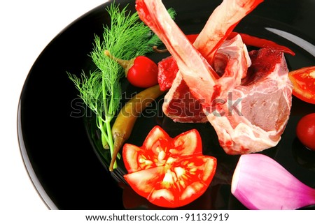 raw lamb chops on plate with vegetables