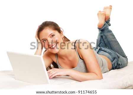 Happy young woman with laptop lying on bed. isolated on white