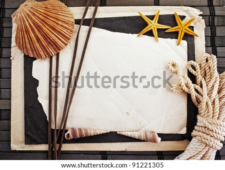 Marine theme frame of paper sheet, big seashell, two sea-stars and sailor rope on a wooden mat.