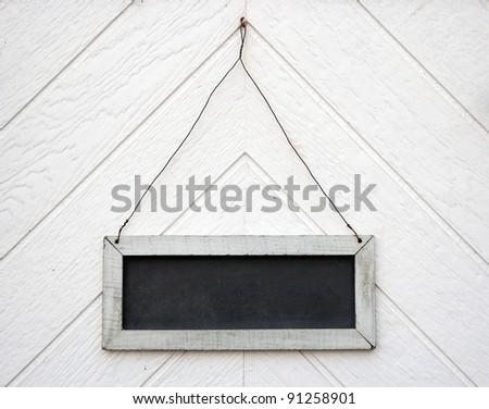 Empty old blackboard sign, hanging on a wooden wall or door