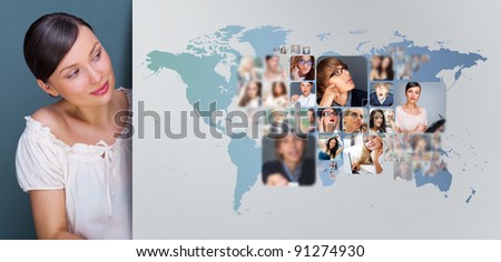 Portrait of young woman standing near big virtual display with world map and lots of photo on it. Network concept
