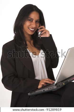 Young adult African-Indian businesswoman in casual office outfit sitting with a notebook computer on her lap on a typist chair on a white background. Not Isolated
