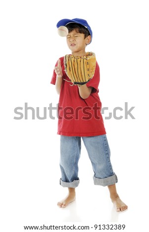 An adorable preschooler making a face while getting bonked by a baseball when trying to catch it.  Motion blur on ball and right arm.  On a white background.