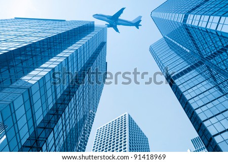 modern glass building with airplane under the sky in hong kong