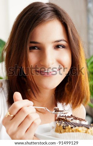 Young beautiful woman with a cake. Closeup portrait. Sitting on sofa at her home