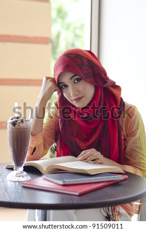 beautiful young muslim woman with lovely smiles reading and having lunch at coffee shop