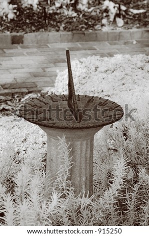 True infrared photo of a metal sundial on a stone column. Sepia tone. Modified camera with 720 nm cutoff filter.