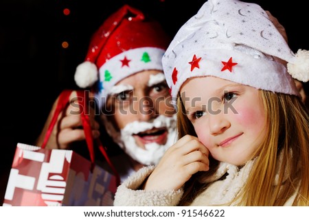Little girl in santa hat and santa claus in background