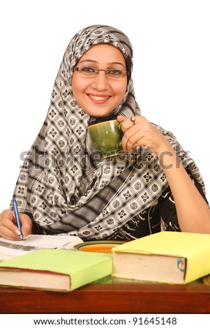 A young muslim girl reading a book and drink tea