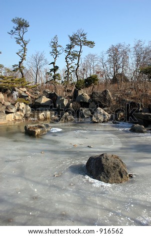 Pond frozen over with waterfall in the background