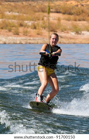 Girl wakeboarder enjoying water sports boarding behind a boat with beautiful Lake Powell in  the background at Glen Canyon National  Recreation Area, Utah, USA