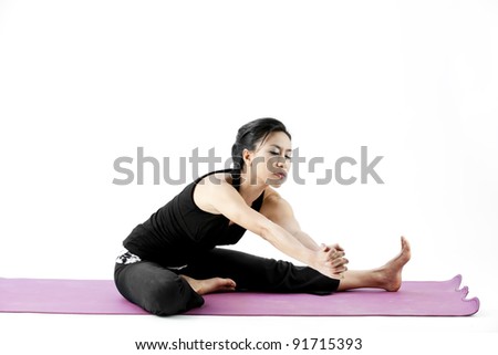 Portrait of a cute young asian female practicing yoga on a mat