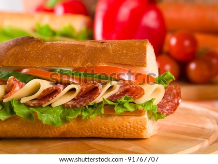 big sandwich with fresh vegetables on wooden board