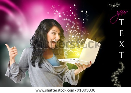Young happy woman with laptop computer and modern design in background, black space on right for your text and glitters you can use.