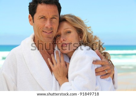 mid aged couple wearing a bathrobe near the sea