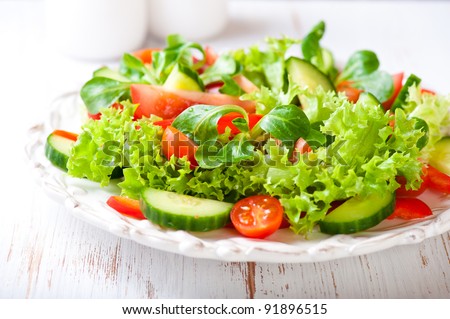 Tasty salad with different tomatoes, red pepper, lambs lettuce, cucumber, lettuce and lambs lettuce. Summer salad. Healthy snack. Concept for a tasty and healthy meal. White wooden background Close up Royalty-Free Stock Photo #91896515