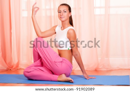 Portrait of pretty young woman doing yoga exercise on mat