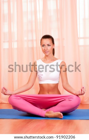 Portrait of pretty young woman doing yoga exercise on mat