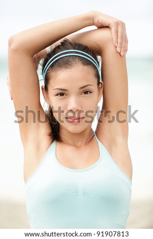 Sport woman training. Fitness woman stretching out during workout on beach. Beautiful mixed race Asian Caucasian female fitness model portrait.