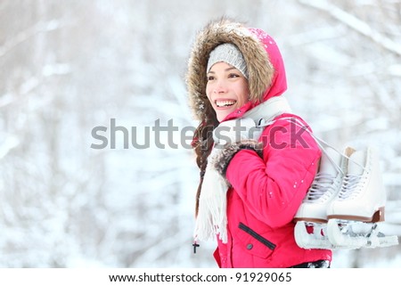 ice skating winter woman holding ice skates outdoors in snow. Beautiful young mixed race chinese asian / caucasian woman