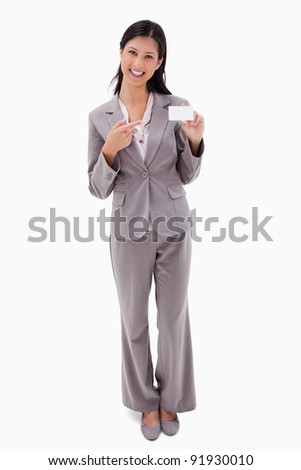 Smiling businesswoman pointing at blank name badge against a white background