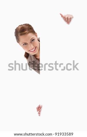 Woman looking around blank sign against a white background