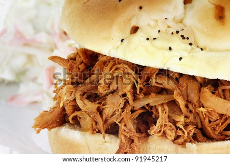 Close up of pulled chicken sandwich with coleslaw in the background. Shallow depth of field.
