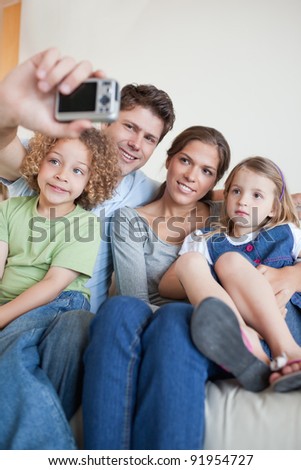 Portrait of a family taking a photo of themselves in their living room