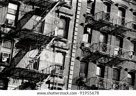 Black and white photo of the exterior of a building in New York with old fire escape.
