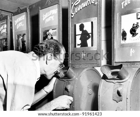 Man looking into a nickelodeon film machine