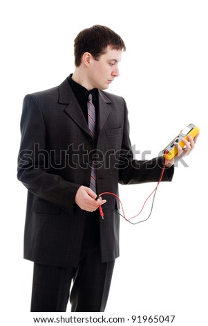 A young man in a suit, looks at the testimony of a multimeter, isolated on a white background.