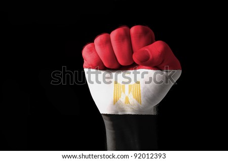 Low key picture of a fist painted in colors of egypt flag