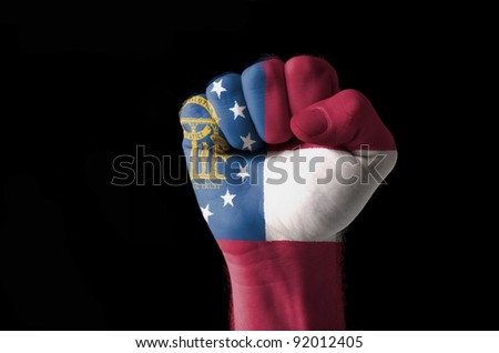 Low key picture of a fist painted in colors of georgia flag